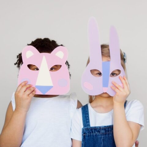 Two Kids Covering Their Faces With a Cutout Animal Mask